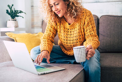 Woman in yellow jumper sitting in front of a laptop