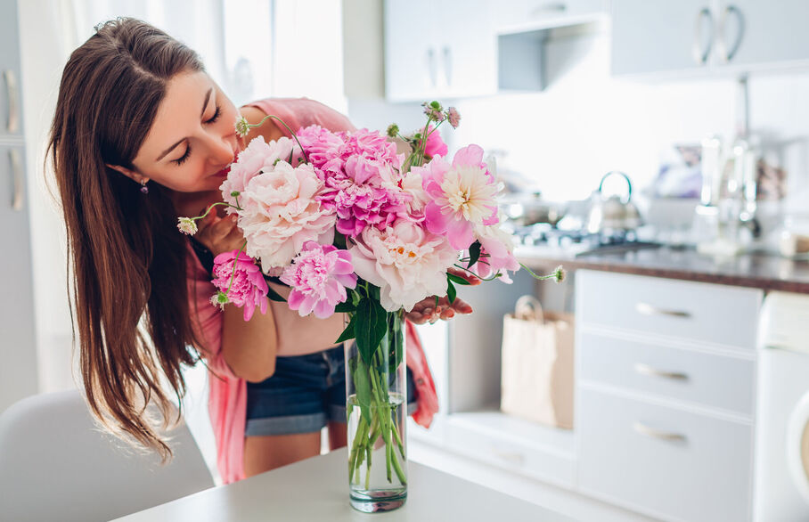 A woman arranging pink flowers on a table