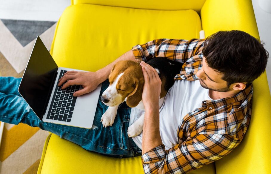 Man with a laptop and dog in his lap