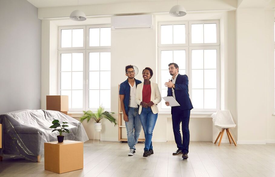 A couple being shown around a packed-up living room