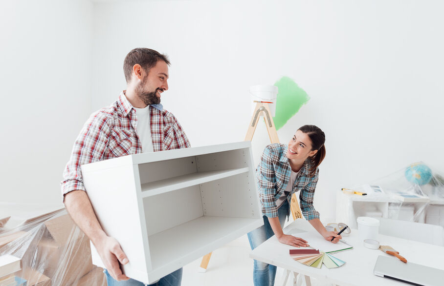 One person carrying a cabinet while another person writes something in a notepad