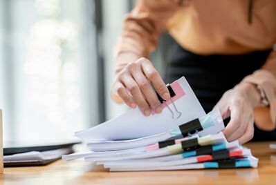 Someone looking through a stack of paper