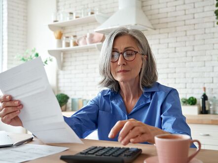 A woman reading a piece of  paper in front of a calculator