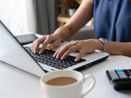 Close up of hands with a laptop at desk