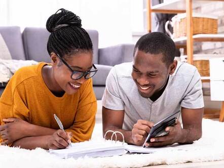 Happy couple lying on floor working out budgets