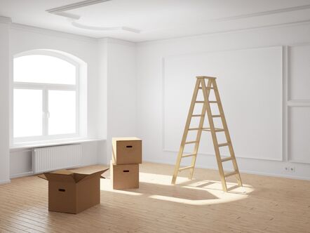 boxes and ladder in empty room, light shining through window 